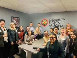 Disability Rights Arizona staff pose for a group photo in front of DRAZ logo