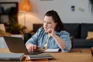 Woman with down syndrome working on her laptop.