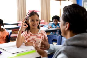 Teacher communicating with student using sign language in elementary school