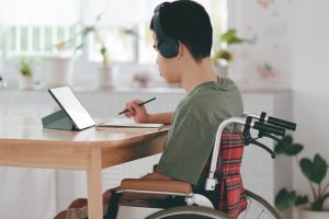 Young man with a disability using mini laptop for learning or studying