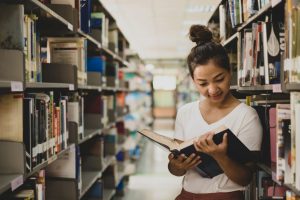Teacher looks at text book in library and thinks about prop 320