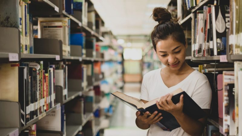 Teacher looks at text book in library and thinks about prop 320