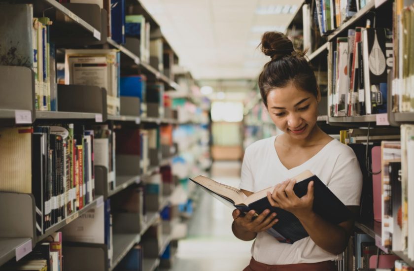 Teacher looks at text book in library and thinks about prop 320