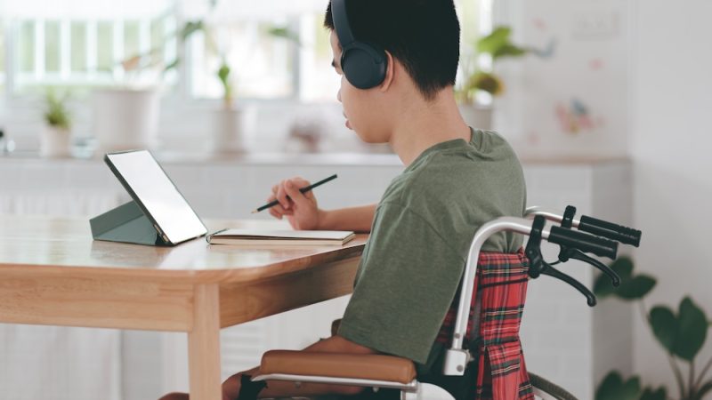 Young man with a disability using mini laptop for learning or studying