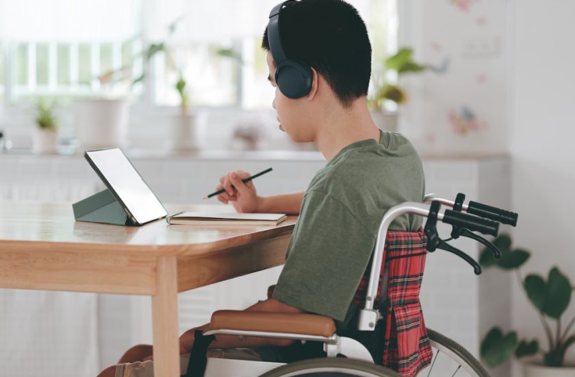 Young man with a disability using mini laptop for learning or studying
