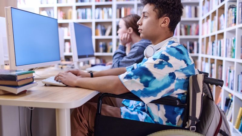 Boy with disability using computer in school